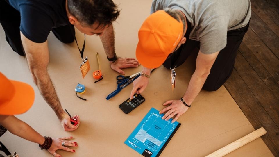 Udeleženci teambuilding programa pregledujejo navodila za izdelavo formule 1