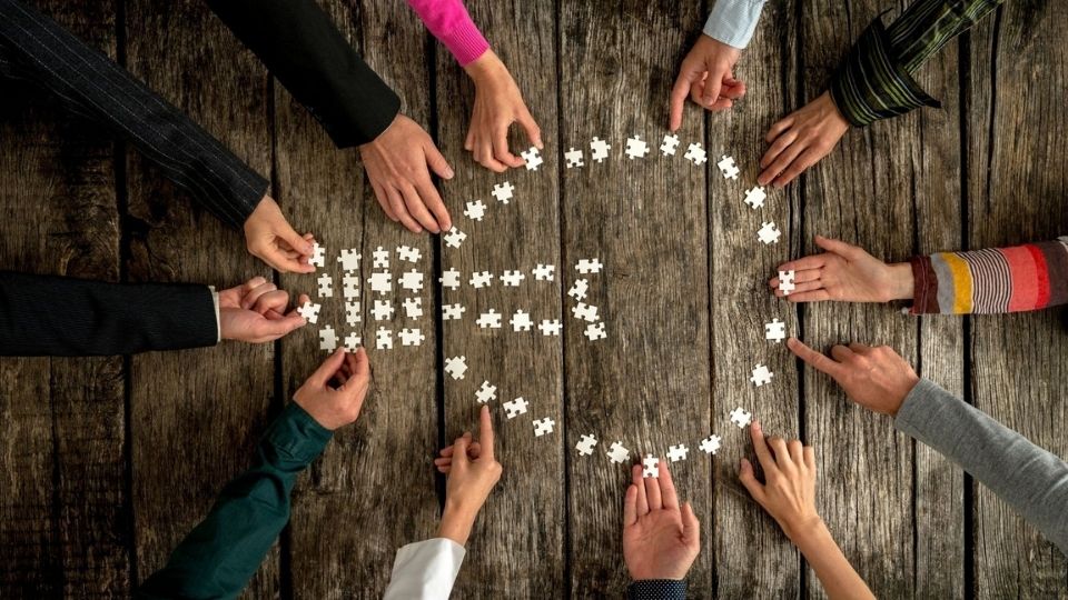 People holding puzzle pieces creating a lightbulb