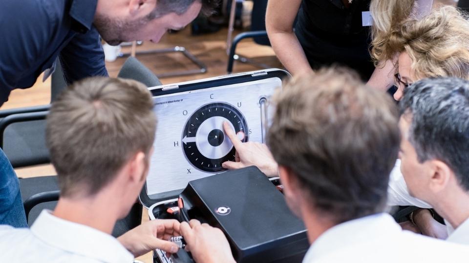 Udeleženci odkrivajo kodo za odprtje zaboja pri timskem programu Skrivnostni zaboj