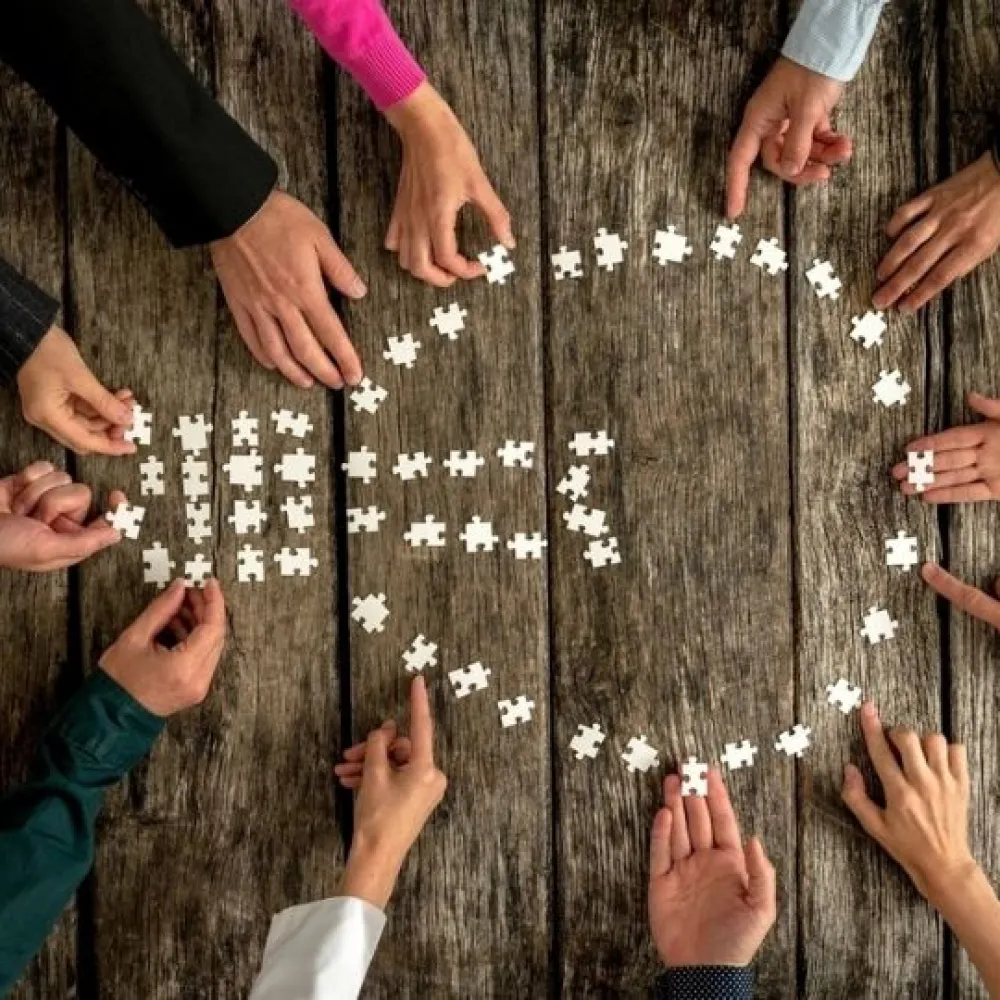 People holding puzzle pieces creating a lightbulb