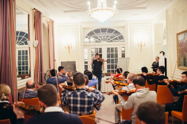 Timski program Harmonija strun - glasbenik uči udeležence igrati violino
